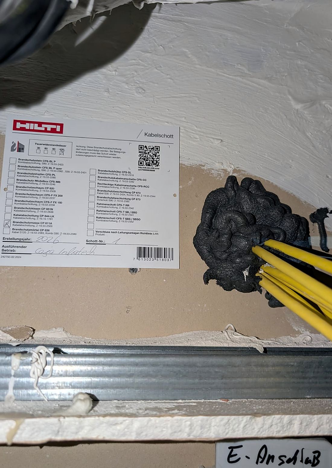 Ausgeführtes Kabelschott mit Hilti-Kennzeichnungsschild, Schott-Nummer und Angabe des ausführenden Betriebs